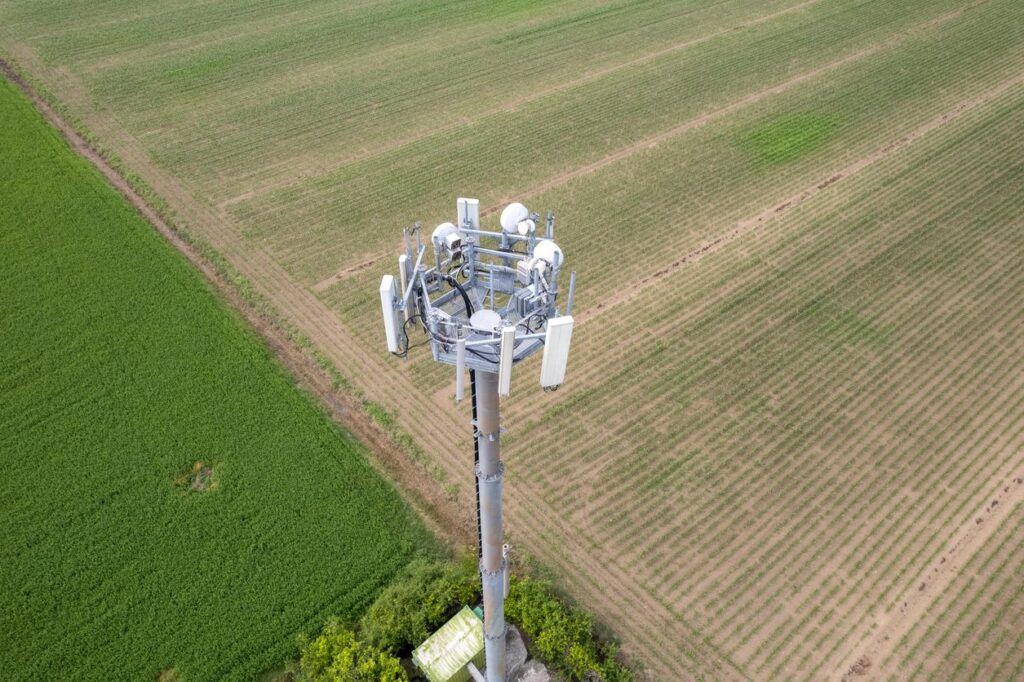 Aerial photo of a cell tower over green farm lands.