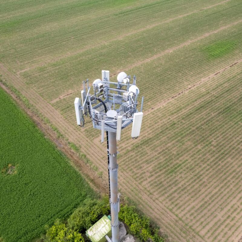 Aerial photo of a cell tower over green farm lands.